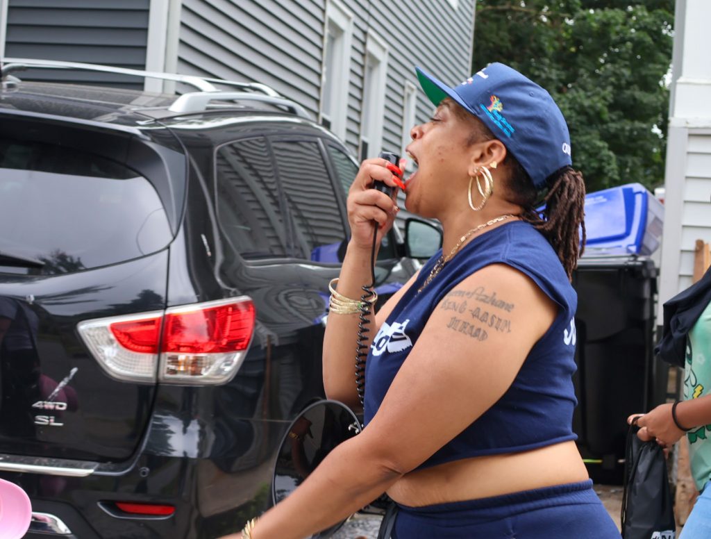 A woman making an announcement on a handheld device connected to megaphone